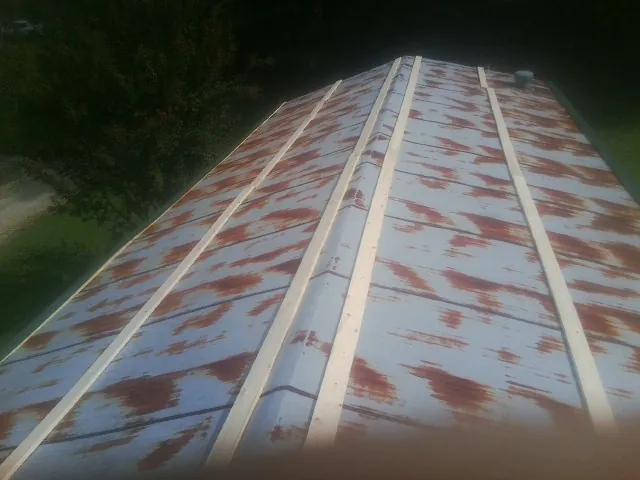 Rusted metal roof panels with new wood purlins before replacement — Storm Damage Roof Repair in Wilmont by Roofing Brothers