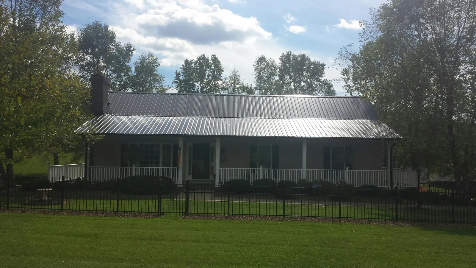 Gray metal roof on a brick ranch with a full width front porch — Gutter Guard Installation work by our crew in Wilmont